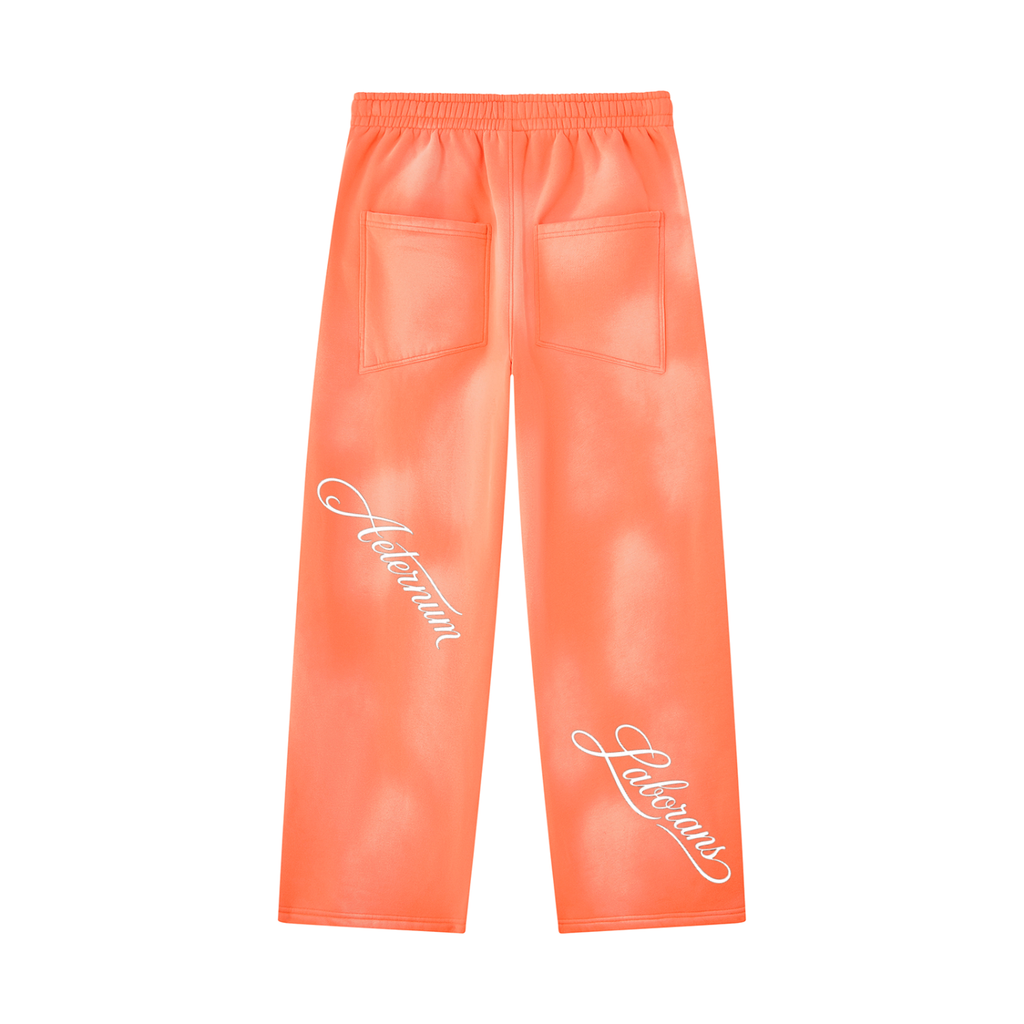 Bright orange faux leather pants with white script text on the lower legs and two back pockets, shown flat on a white background.