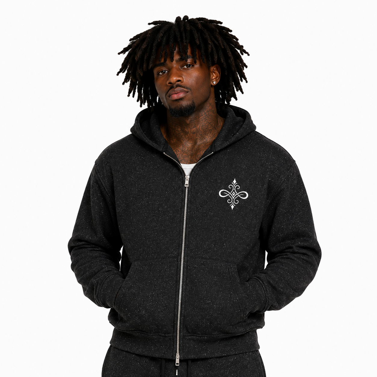 A man with black dreadlocks wearing a dark charcoal zip-up hoodie with a white embroidered Celtic knot design on the left chest, photographed against a solid white background.