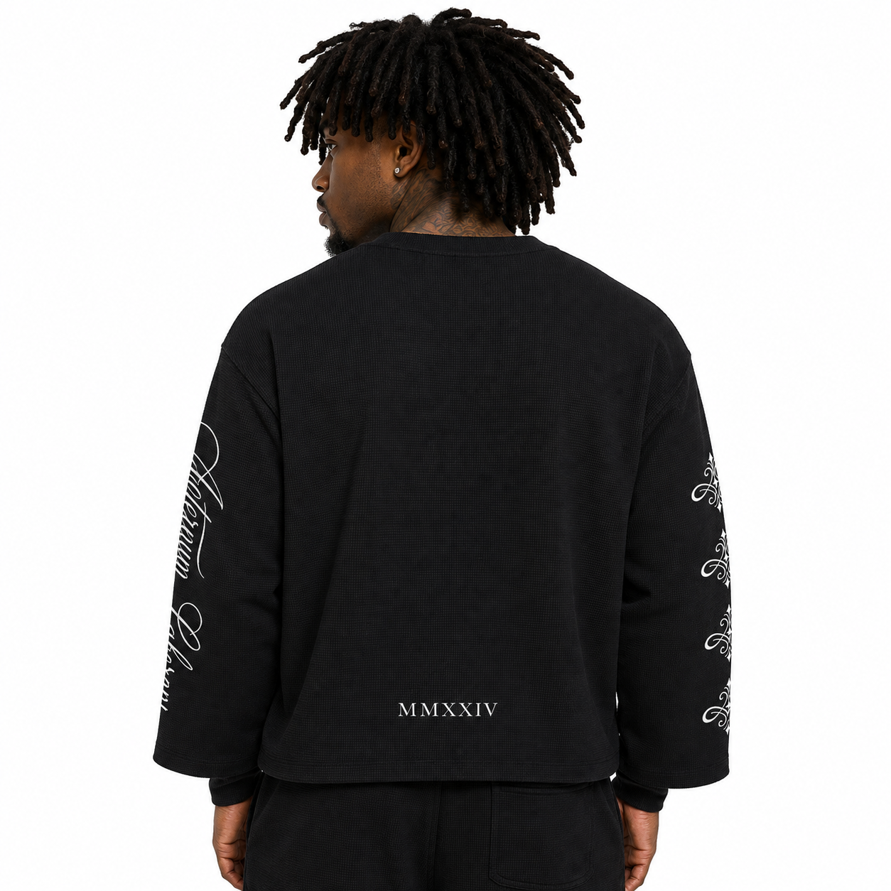 A man viewed from the back wearing a black crewneck sweatshirt with white script graphics on the sleeves and 'MMXXIV' printed near the lower back, against a plain white background.