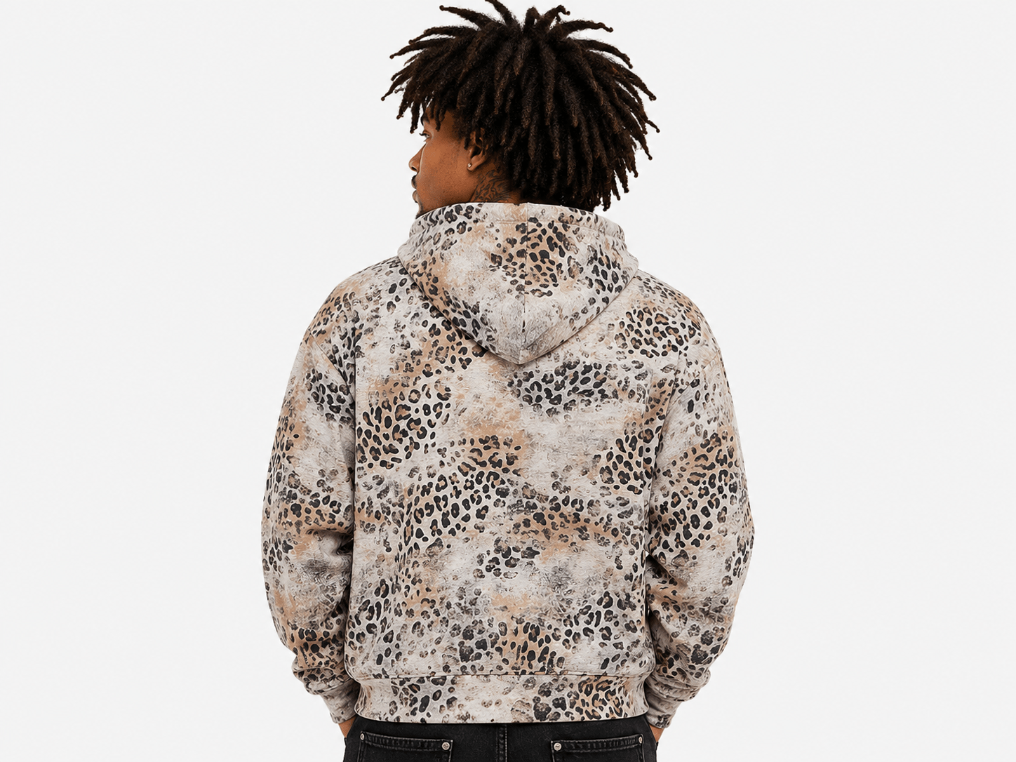 A person shown from the back wearing a hooded sweatshirt with an allover leopard print pattern in beige, brown, black, and off-white, against a plain light gray background.