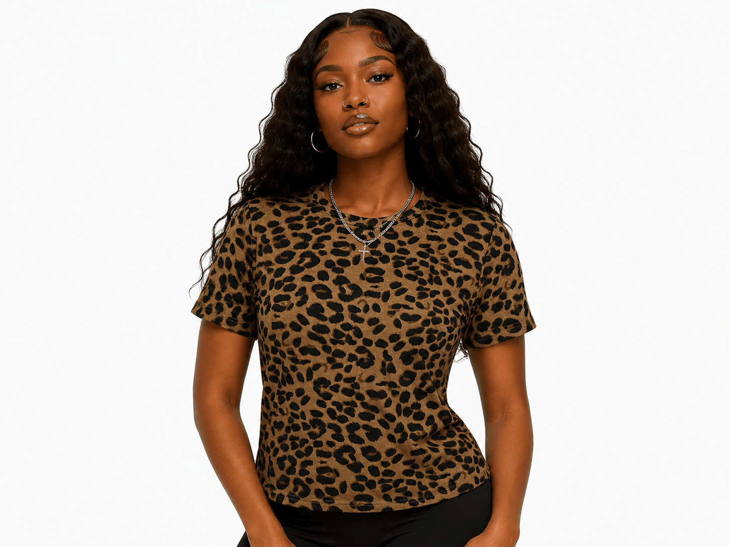 A woman with long, curly black hair wearing a brown and black leopard print short-sleeve top, standing against a solid white background.