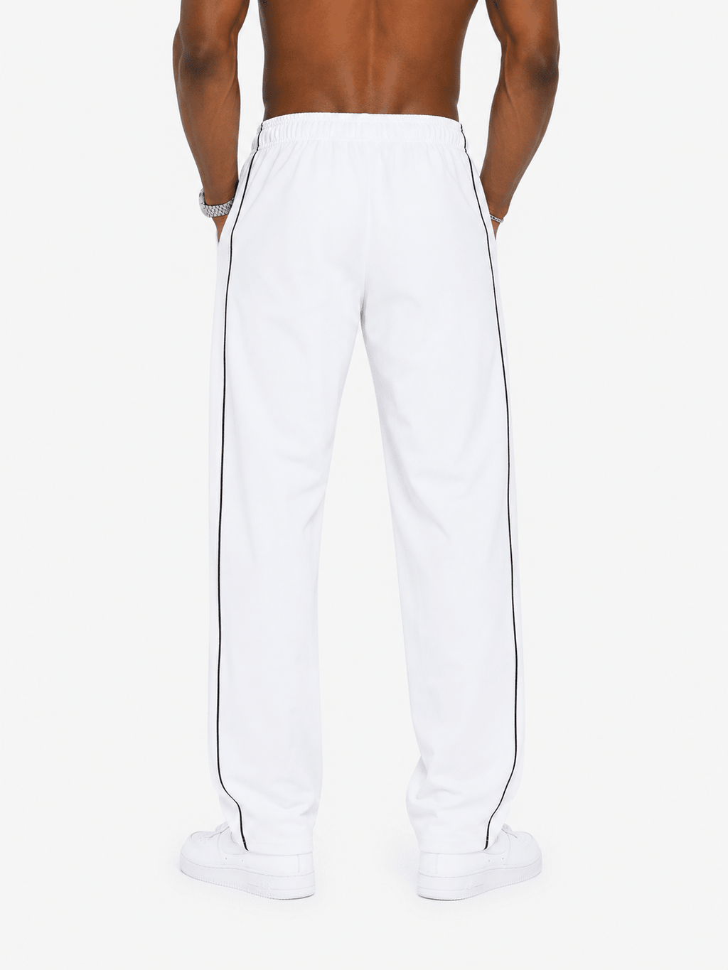White track pants with a double black stripe down the side, shown on a model from the back against a light gray background.