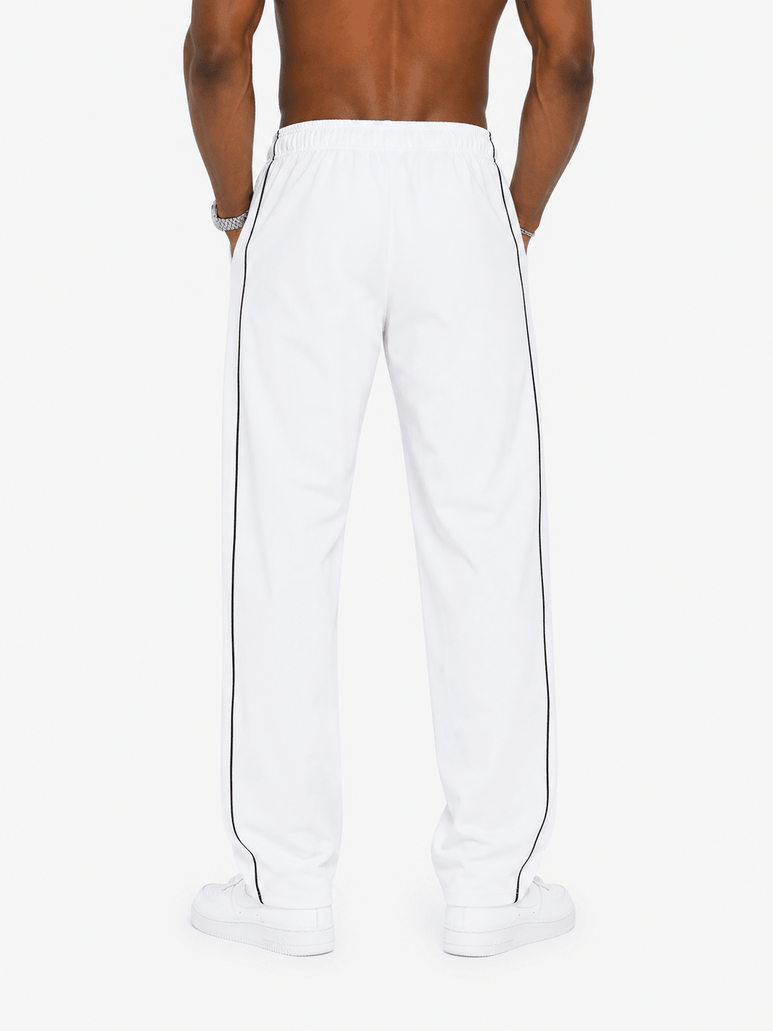 White track pants with a double black stripe down the side, shown on a model from the back against a light gray background.