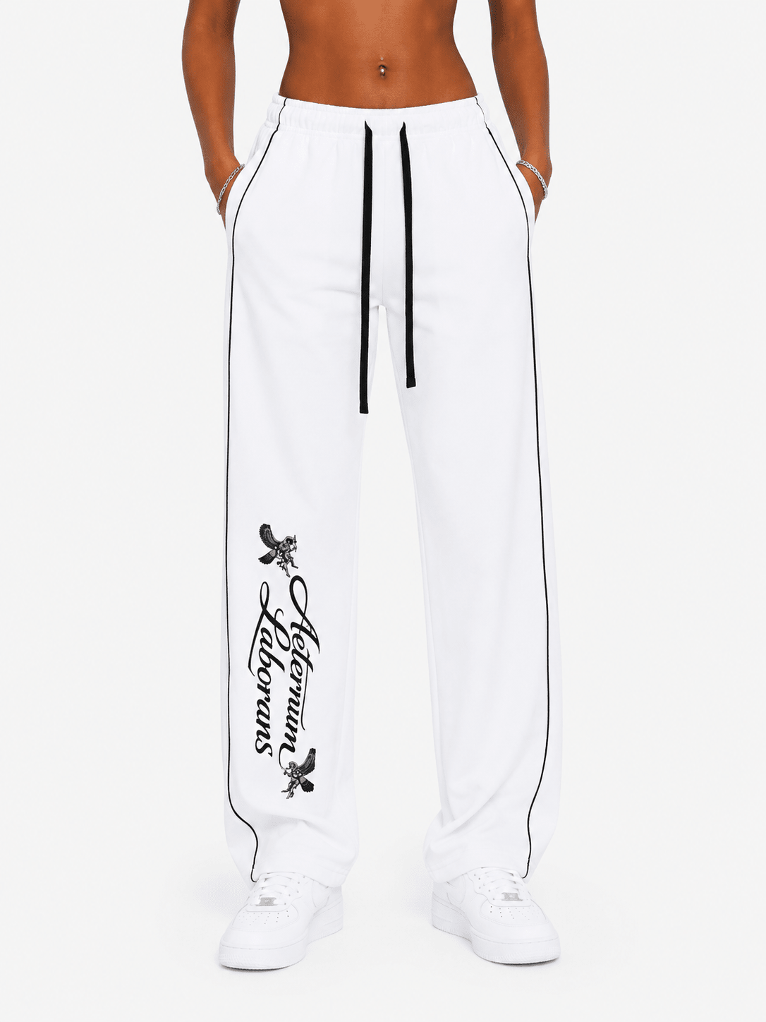 White wide-leg sweatpants with black side piping, a black drawstring, and a black vertical 'Allium Flowers' graphic on the left leg, shown on a model against a light gray background.