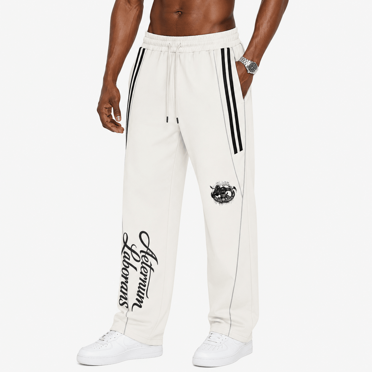 A model wearing off-white track pants with black side stripes, a black graphic on the right thigh, and vertical script branding on the left leg, paired with white sneakers against a light gray background.