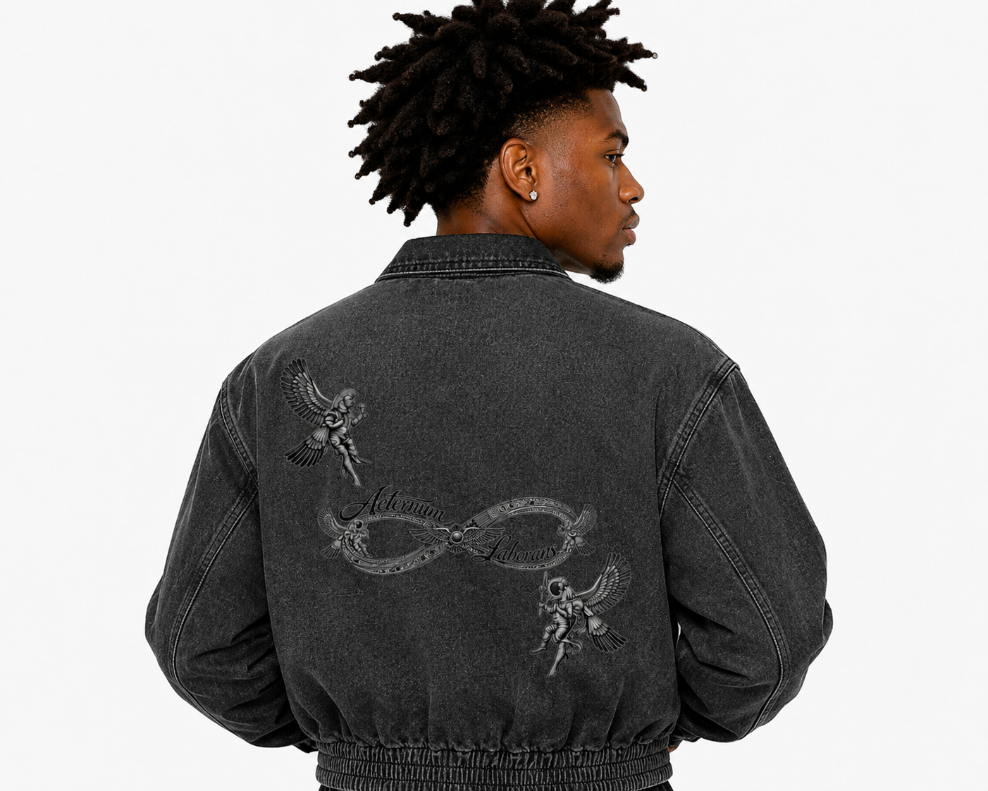 Person wearing a black denim jacket with embroidered designs on the back, on a white background