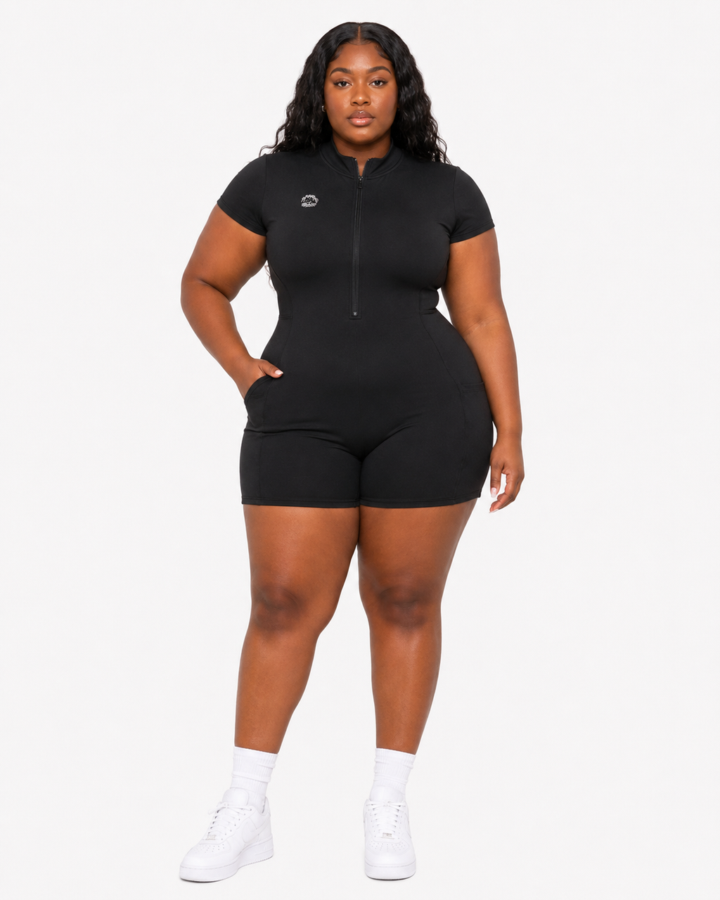 Person wearing a black onesie with white sneakers on a white background
