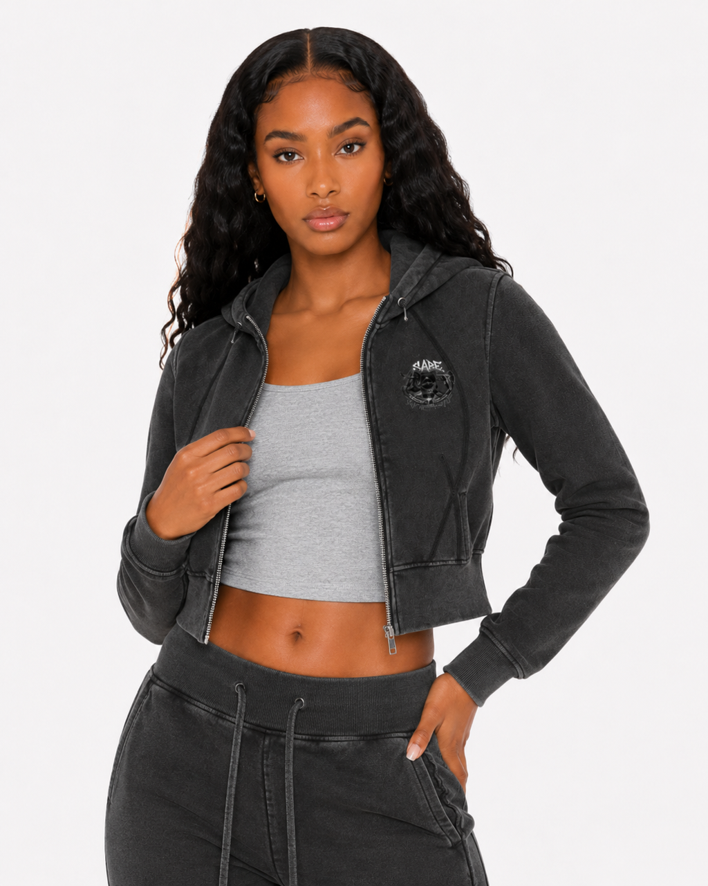 Woman wearing a black cropped hoodie and gray athletic top on a white background