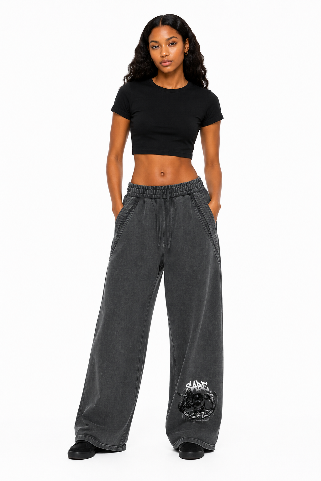 Woman wearing a black crop top and gray sweatpants on a white background