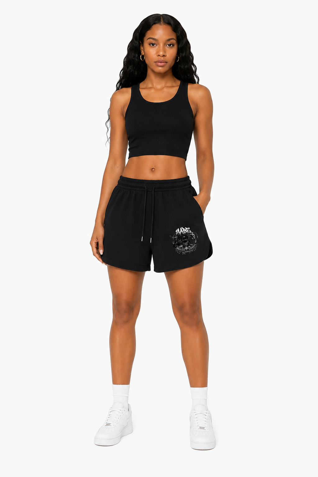 Woman wearing a black athletic outfit with shorts and a crop top on a white background