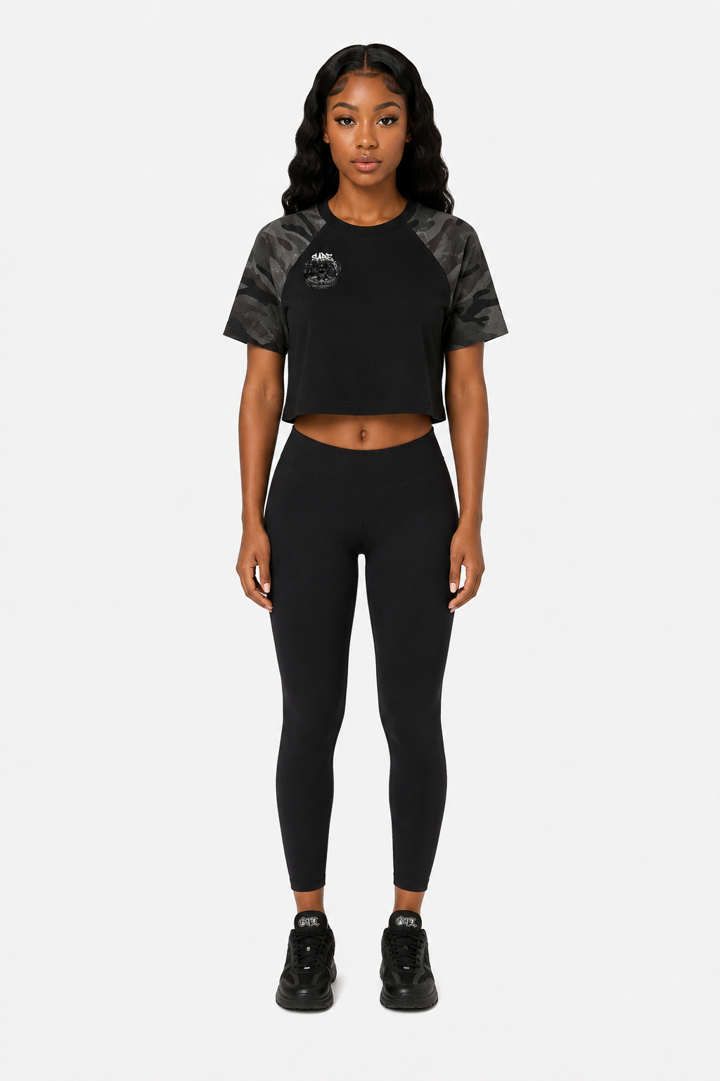 Woman wearing a black athletic outfit with gray sleeves on a white background