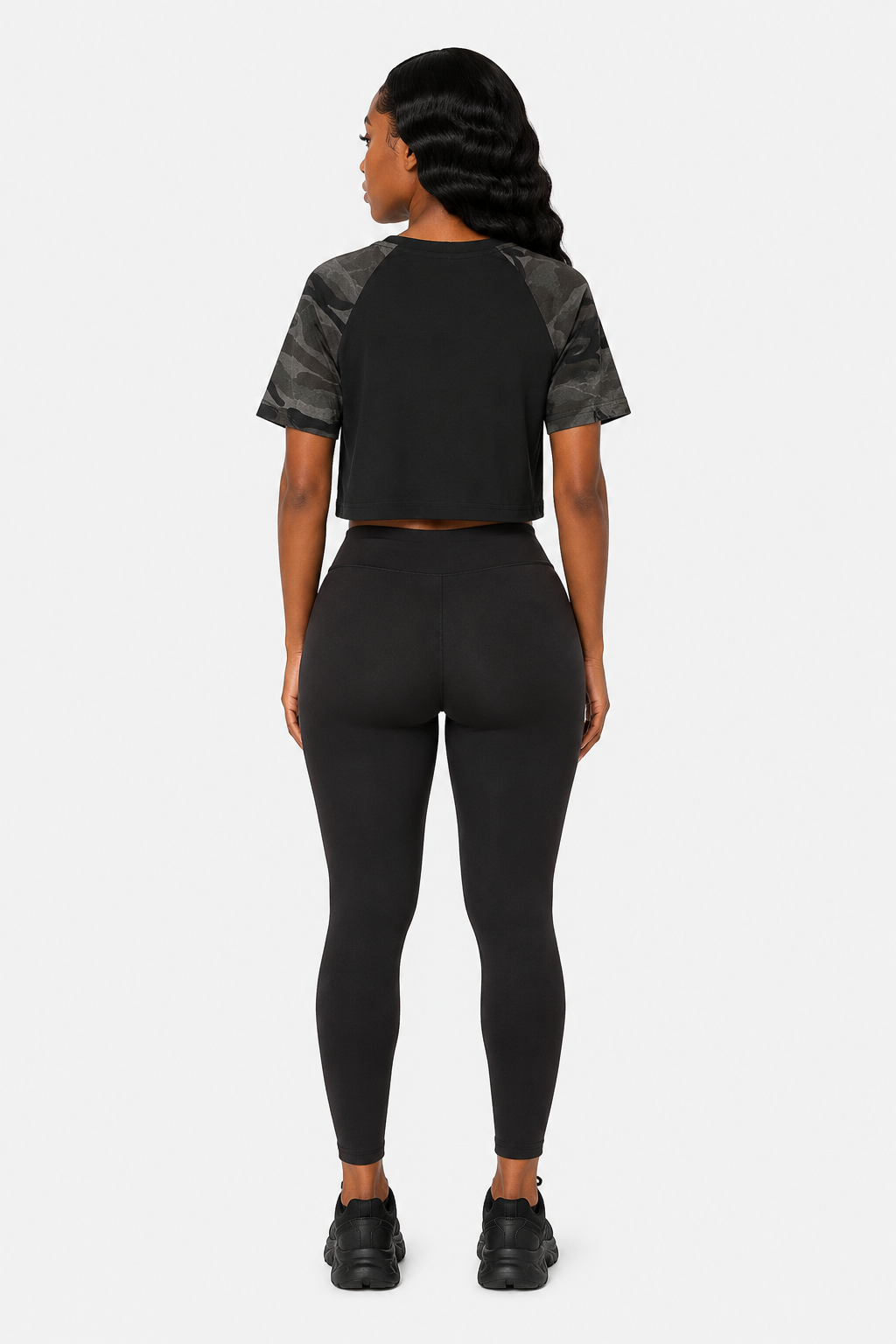 Person wearing a black athletic outfit with gray sleeves on a white background