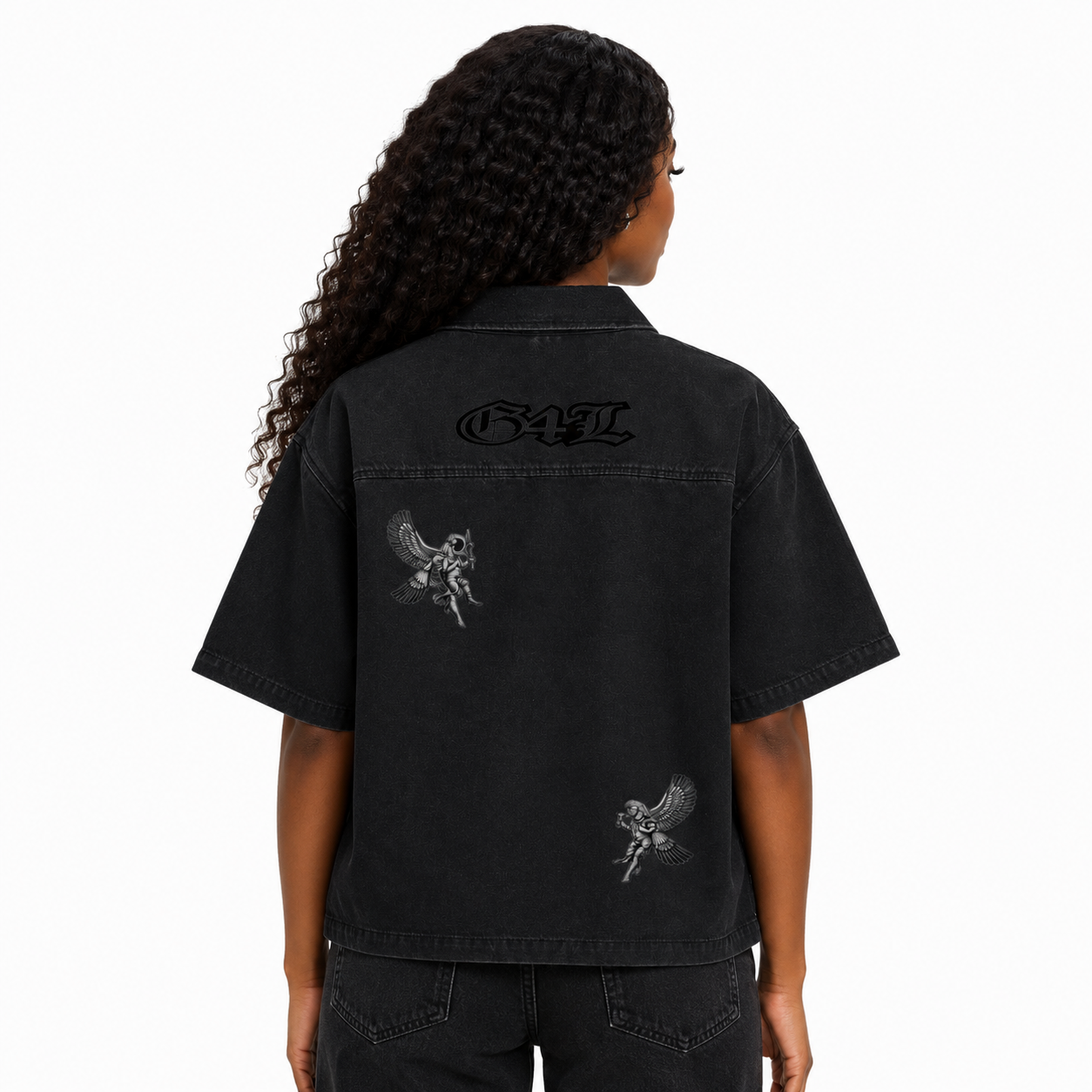 Person wearing a black denim shirt with graphics and text on the back, on a white background