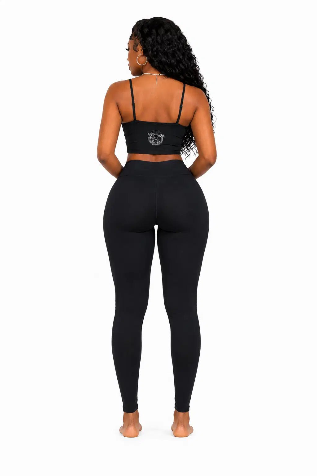 Person wearing a black sports bra and leggings set on a white background