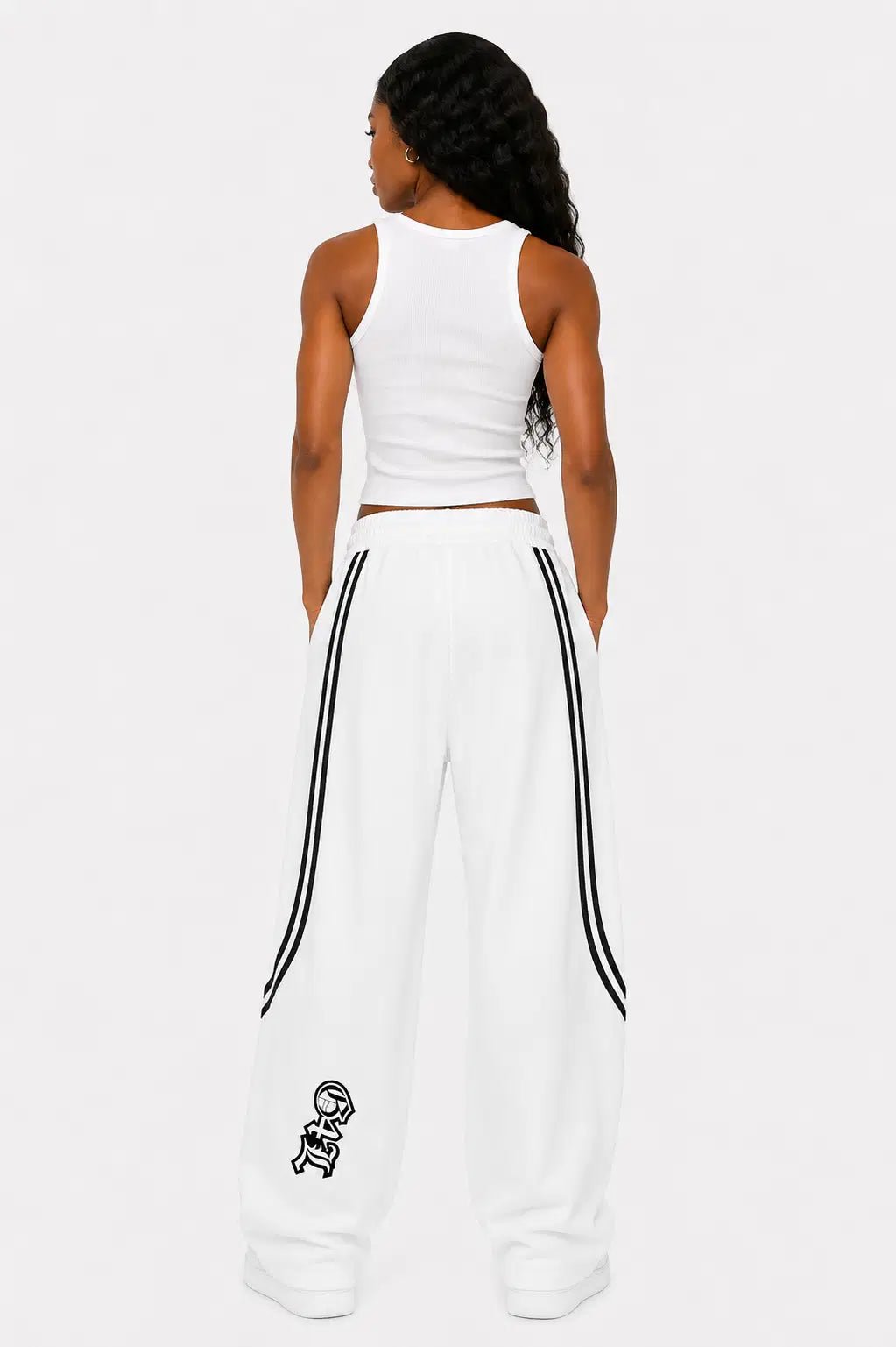 Woman wearing a white sleeveless top and wide-leg pants with black stripes on a white background