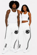 Two people wearing matching white outfits with black designs on a plain background