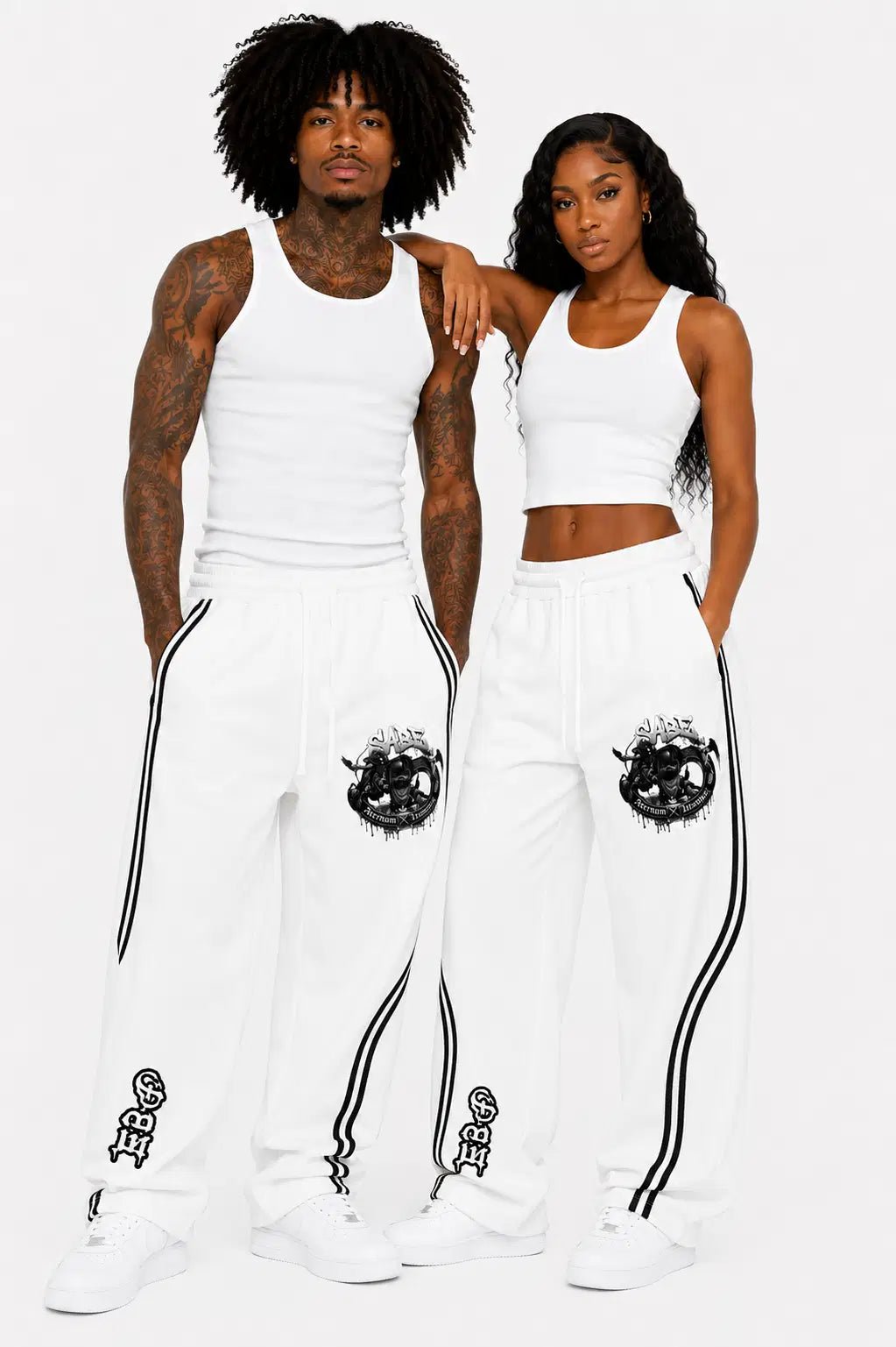 Two people wearing matching white outfits with black designs on a plain background