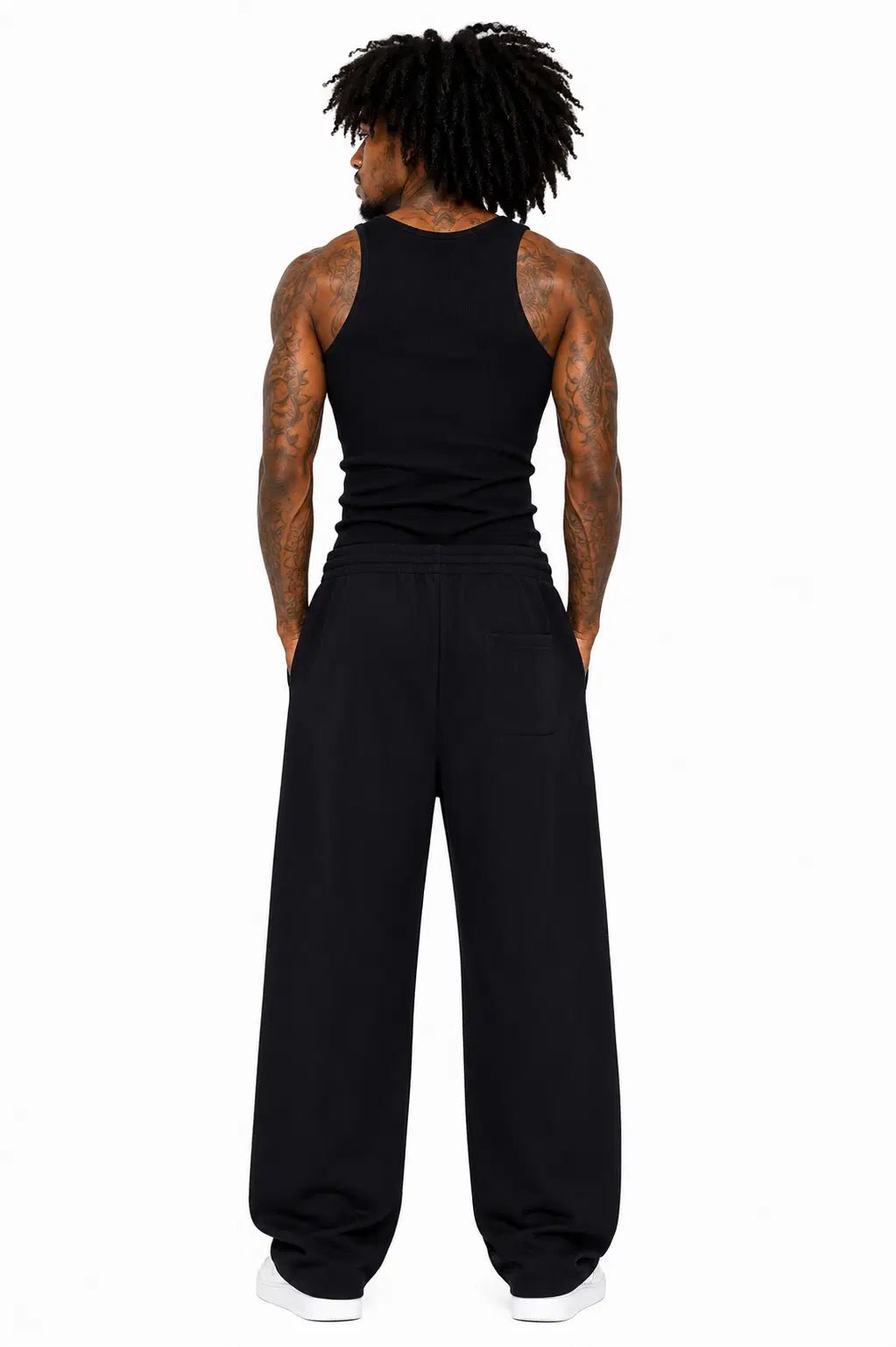 Person wearing a black tank top and black pants on a white background