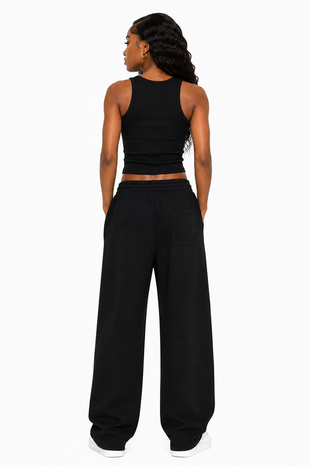 Person wearing a black tank top and wide-leg pants on a white background