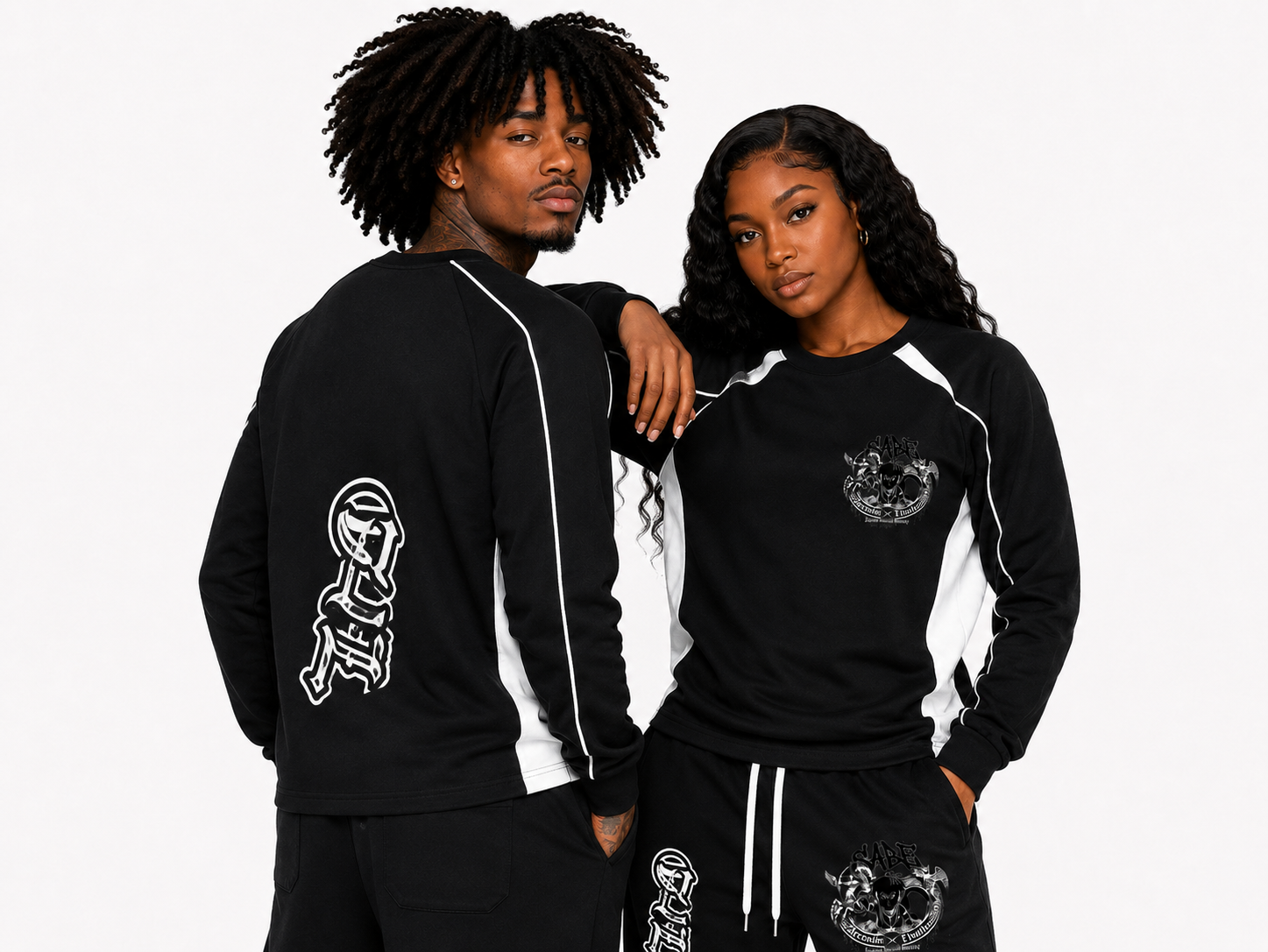 Two people wearing black tracksuits with white designs on a plain background