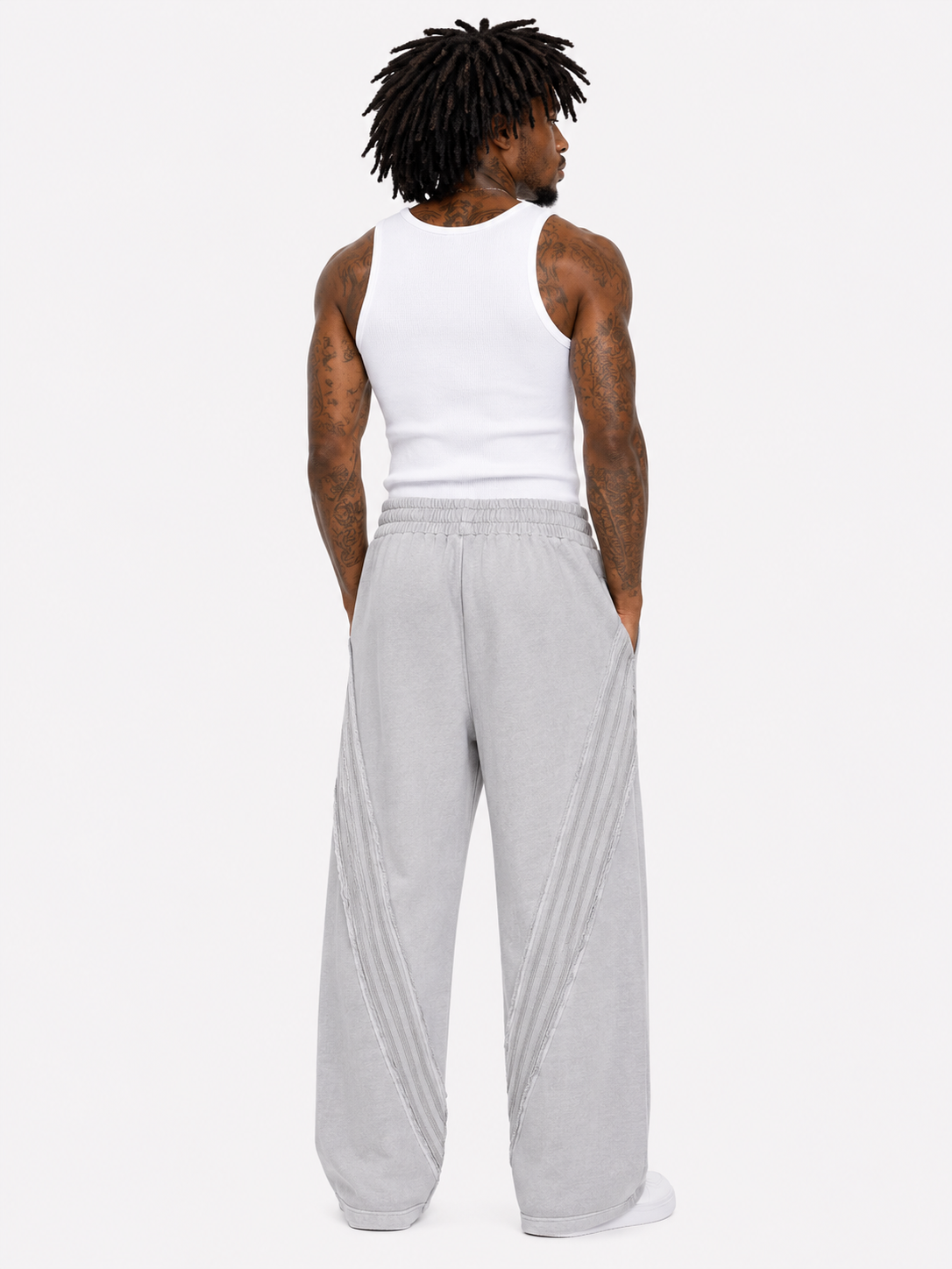 Person wearing a white tank top and gray sweatpants on a white background