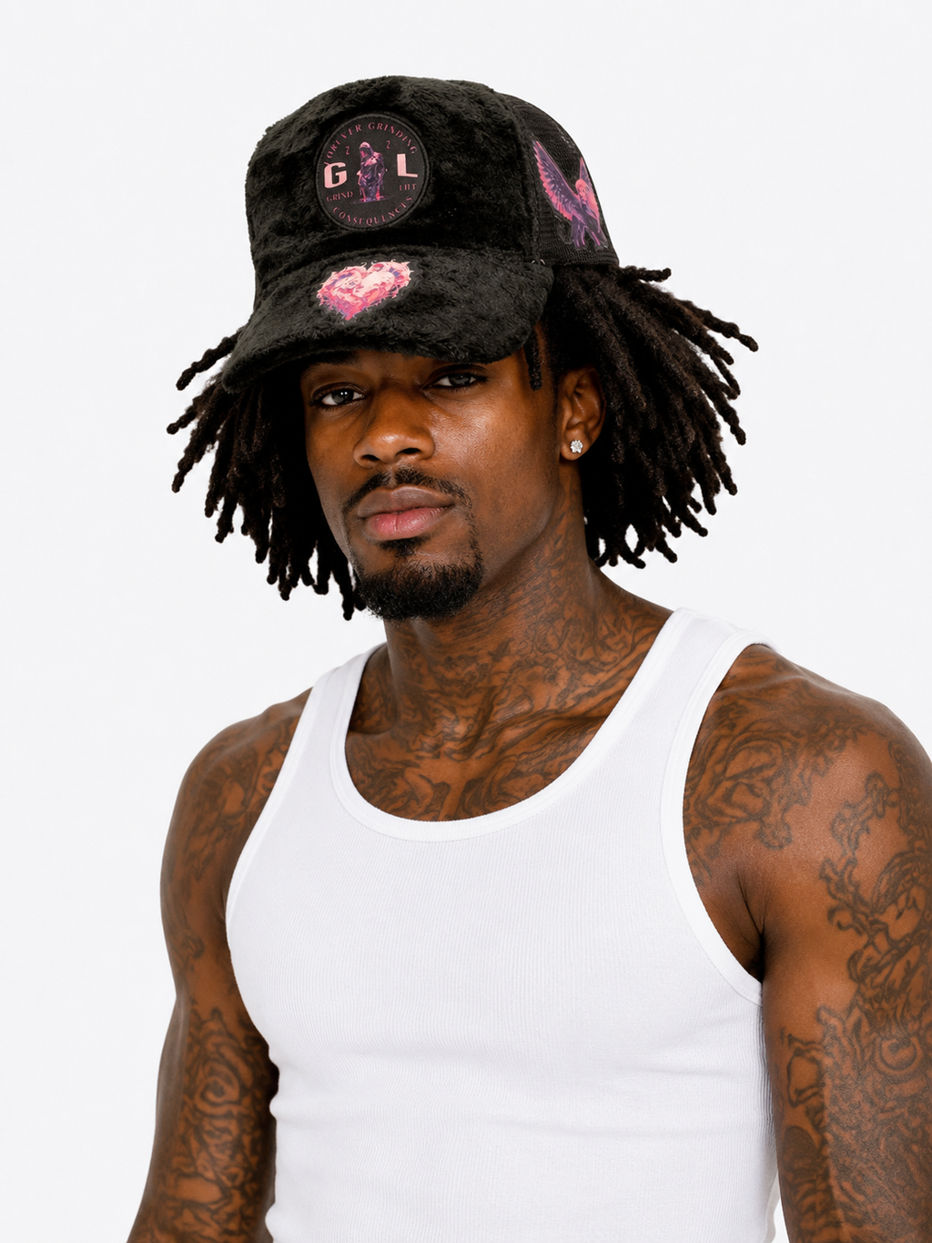 Man wearing a black cap with pink designs and a white tank top on a white background