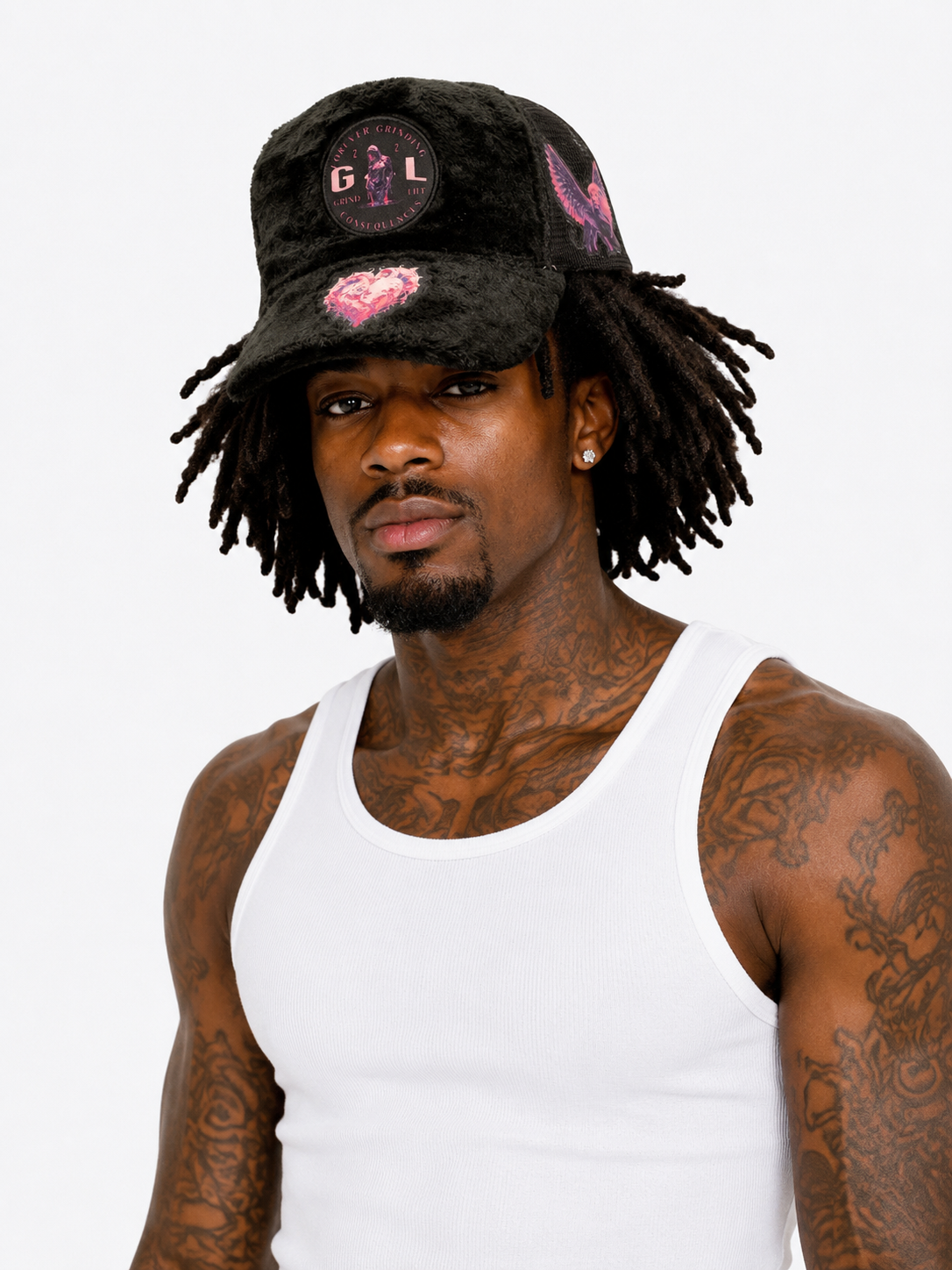 Man wearing a black cap with pink designs and a white tank top on a white background