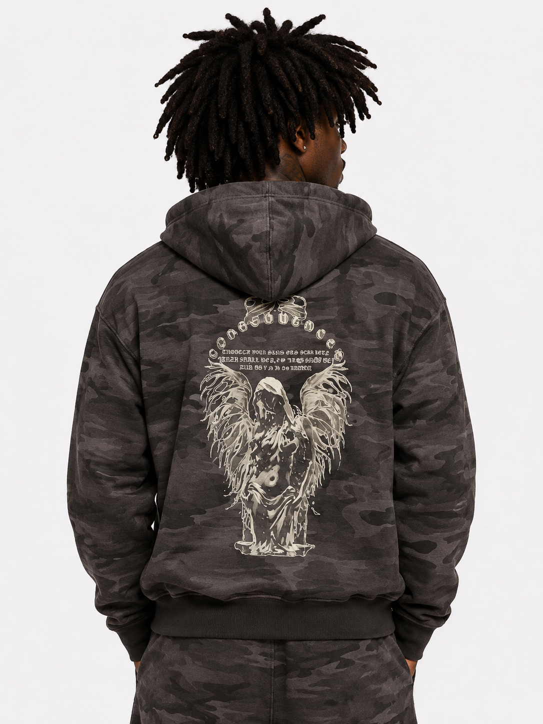 Person wearing a dark camouflage hoodie with an angel design on the back against a white background