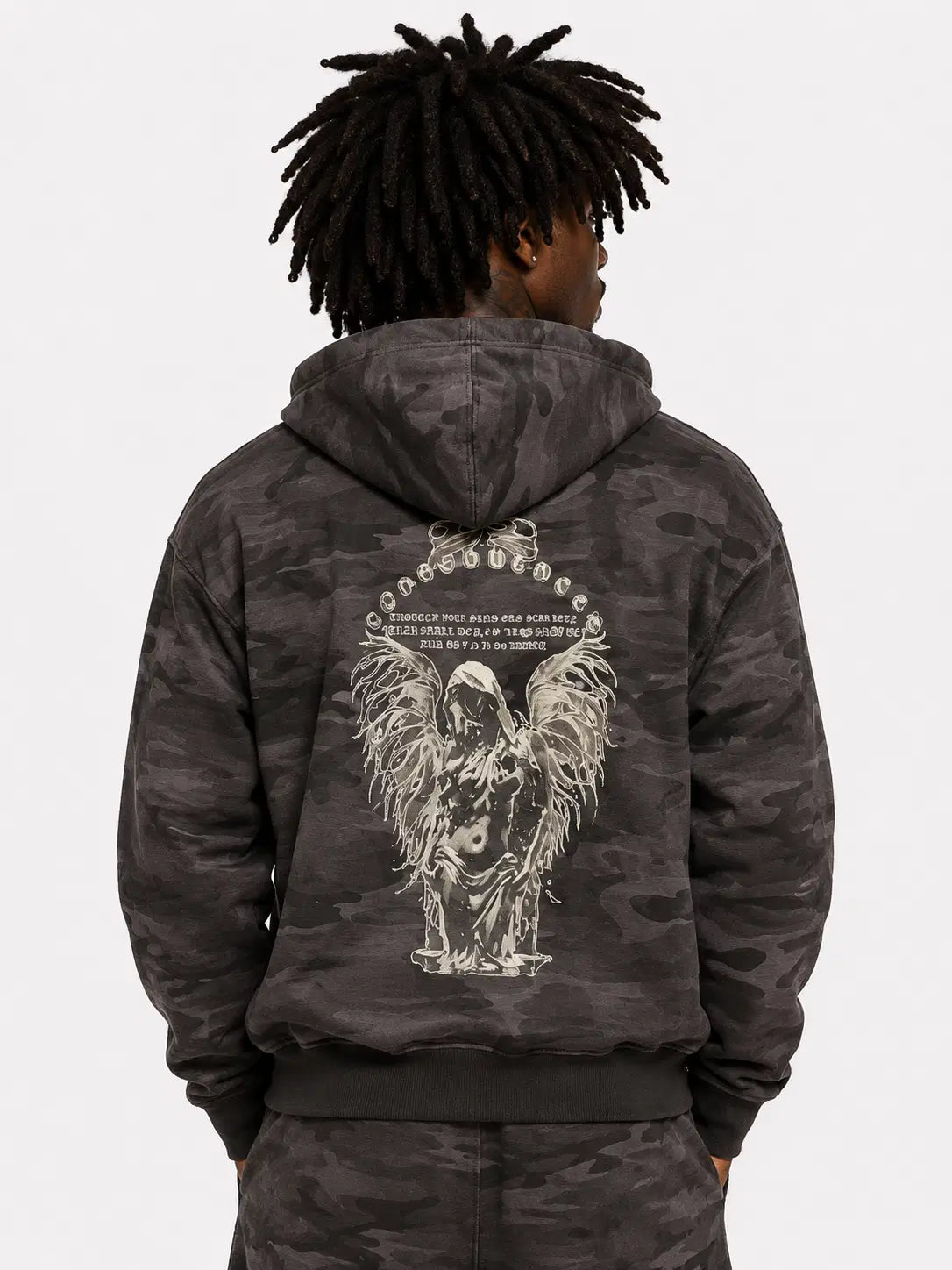Person wearing a dark camouflage hoodie with an angel design on the back against a white background