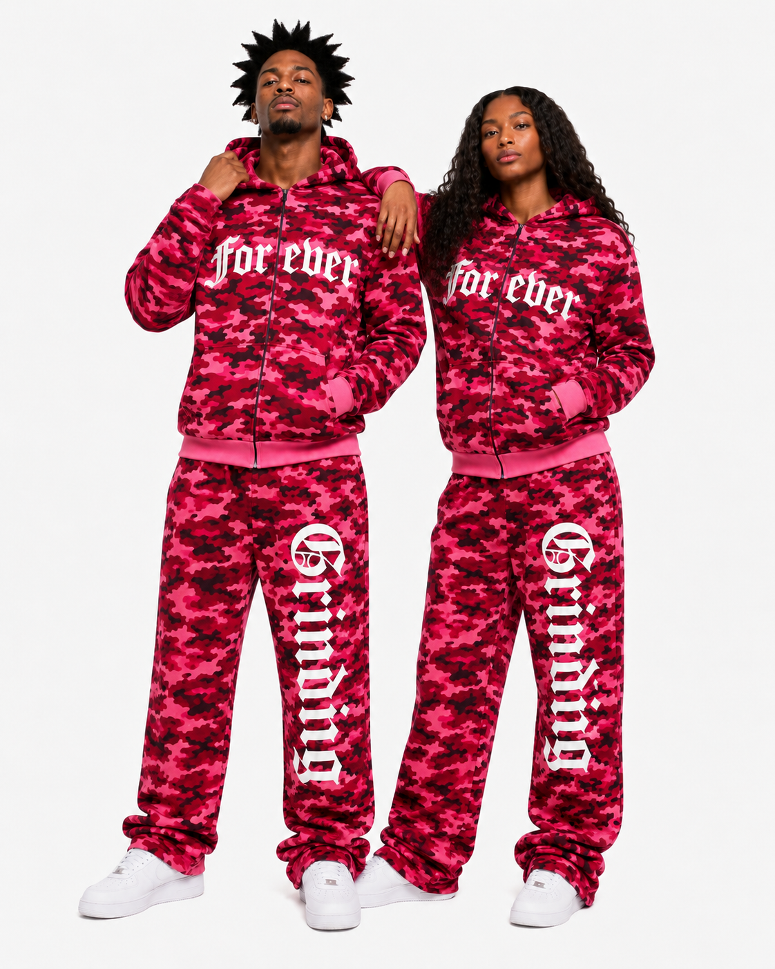 Two people wearing matching red camouflage tracksuits with text on a white background