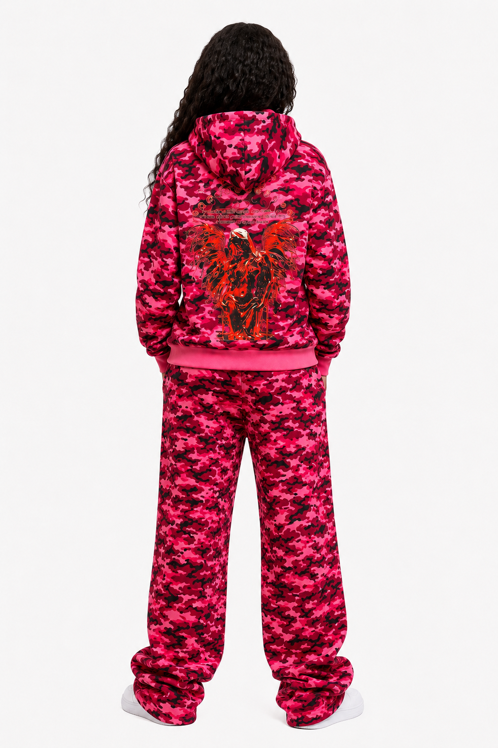 Person wearing a pink camouflage hoodie and pants set on a white background