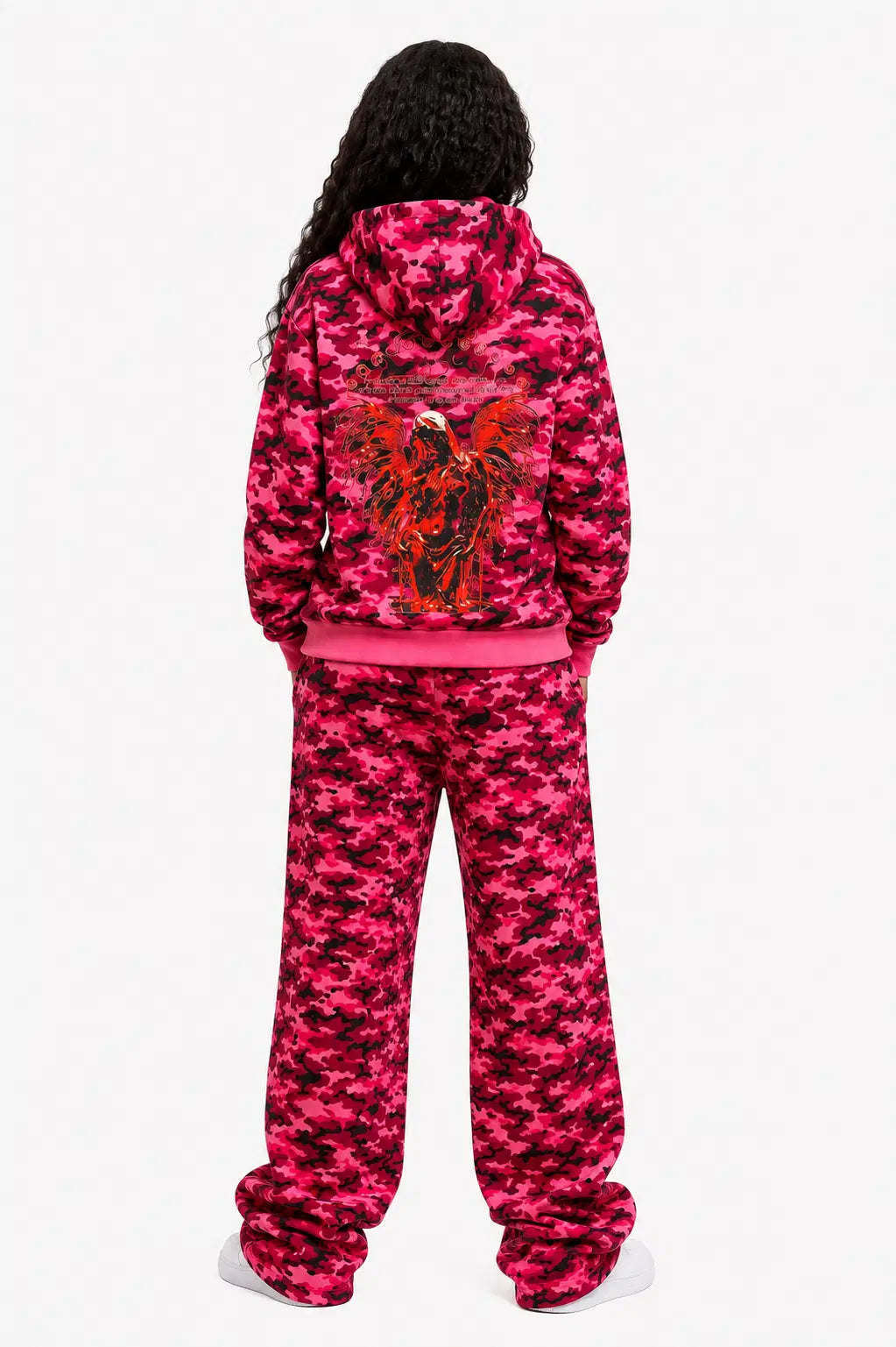 Person wearing a pink camouflage hoodie and pants set on a white background