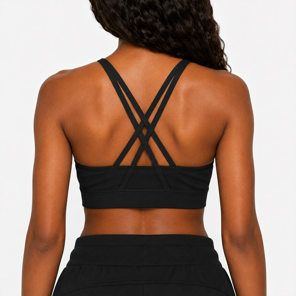 Black sports bra with criss-cross straps worn by a person on a plain background