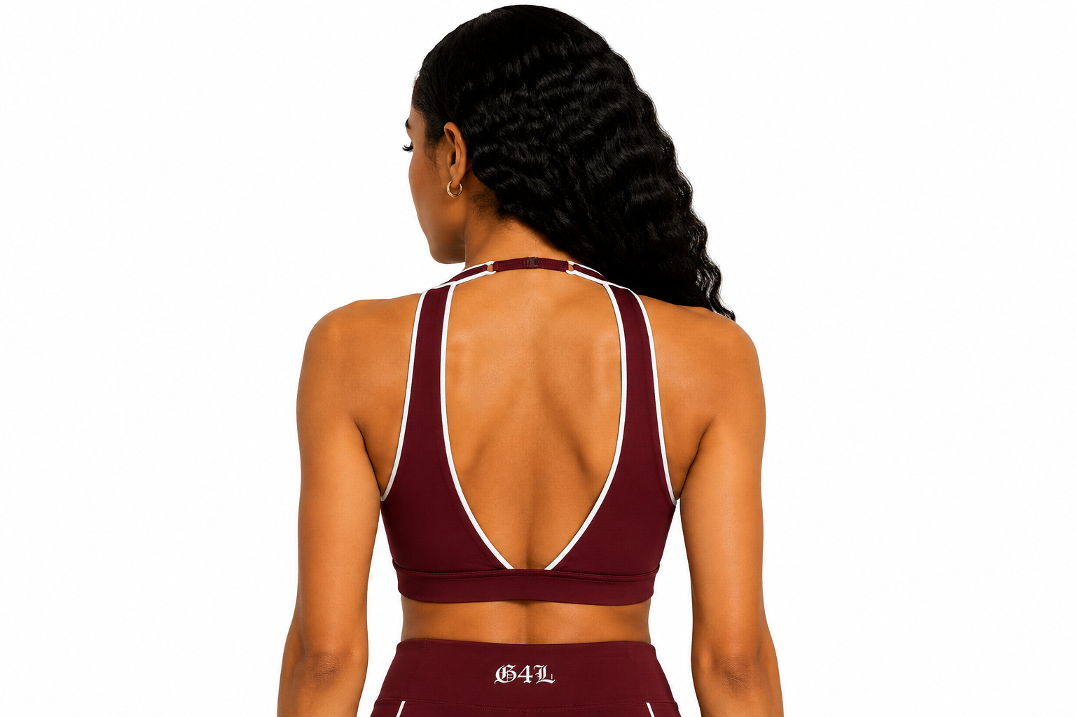 Woman wearing a maroon sports bra with thin straps on a white background