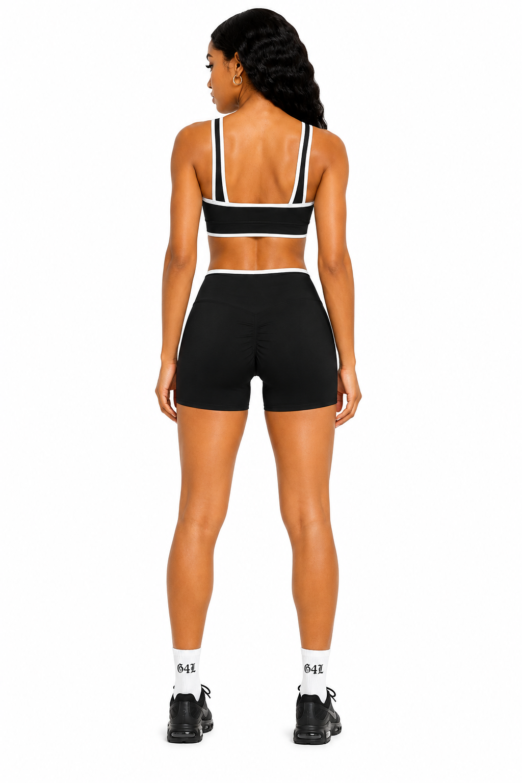 Person wearing a black sports bra and shorts set on a white background