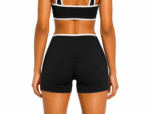 Person wearing a black sports bra and shorts on a white background