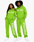 Two people wearing matching green tracksuits with text on a white background