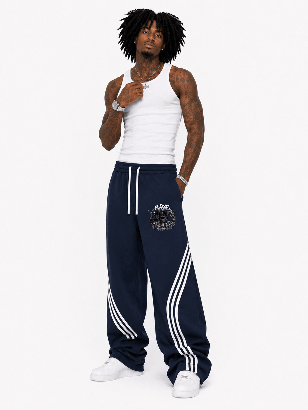 Man wearing navy tracksuit with white stripes and white tank top on a white background