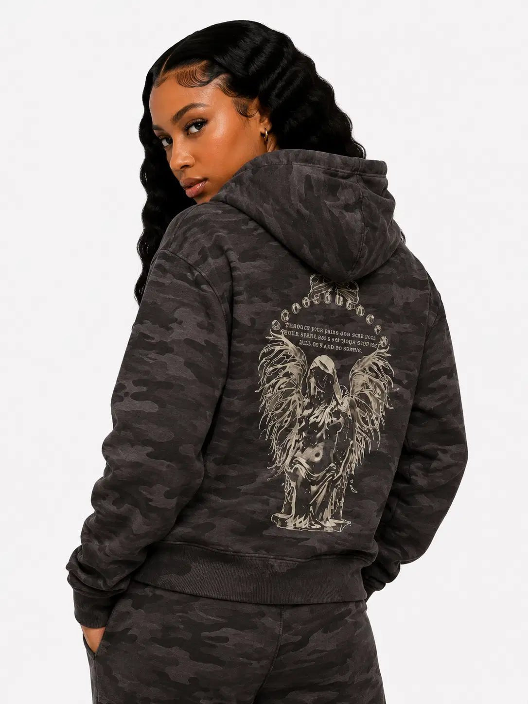 Person wearing a black camouflage hoodie with a graphic design on the back, on a white background