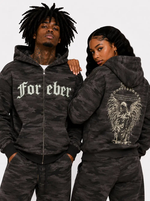 Two people wearing matching camouflage hoodies with text and graphics on a plain background