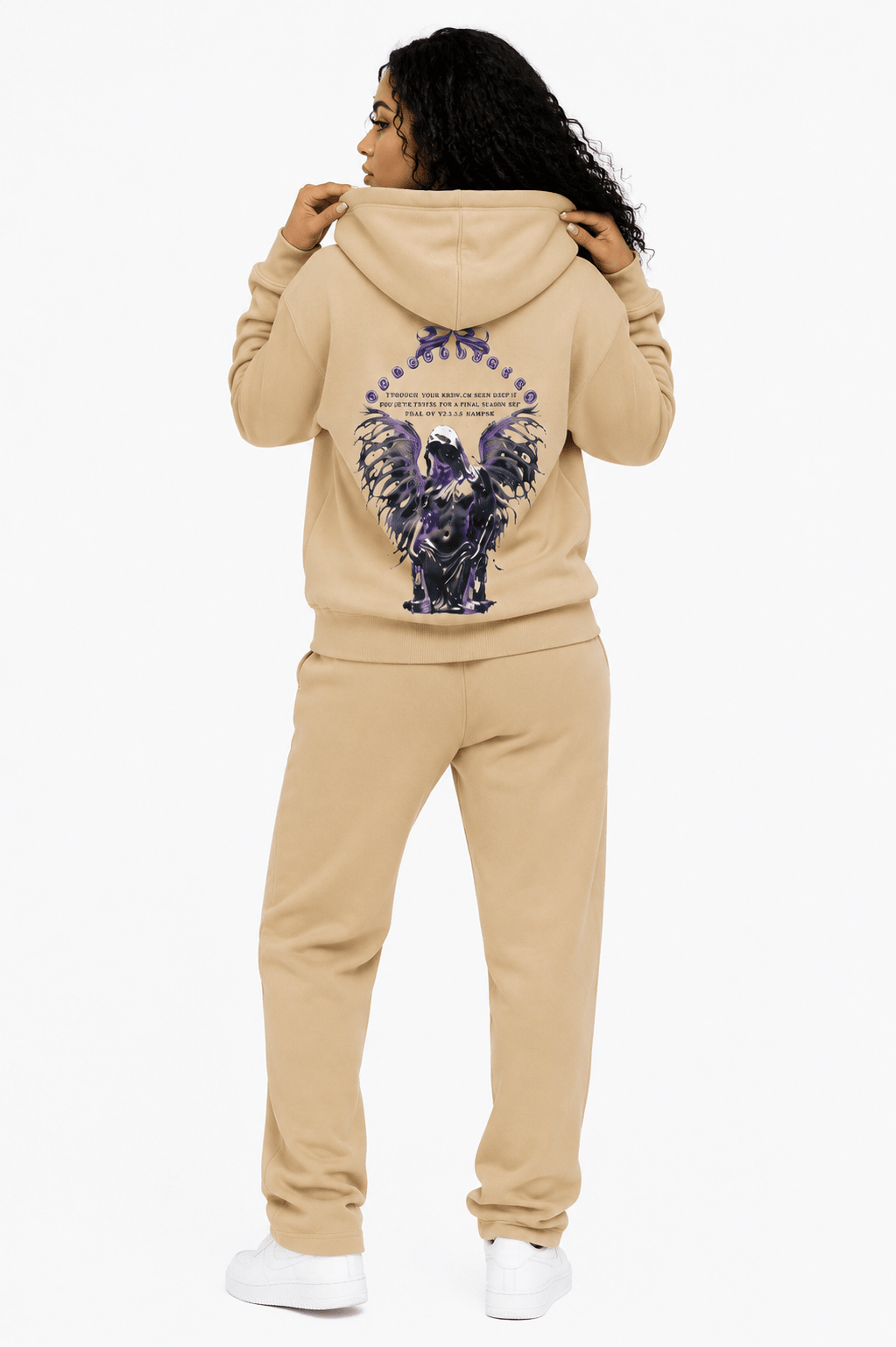 Person wearing a beige hoodie with a graphic design on the back, standing against a white background
