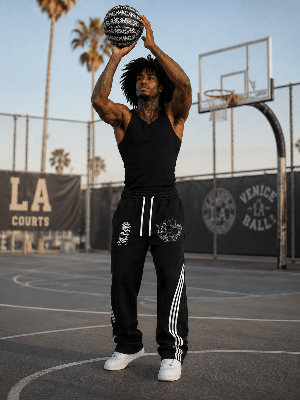 Person holding a basketball on a court with palm trees and 'LA Courts' in the background
