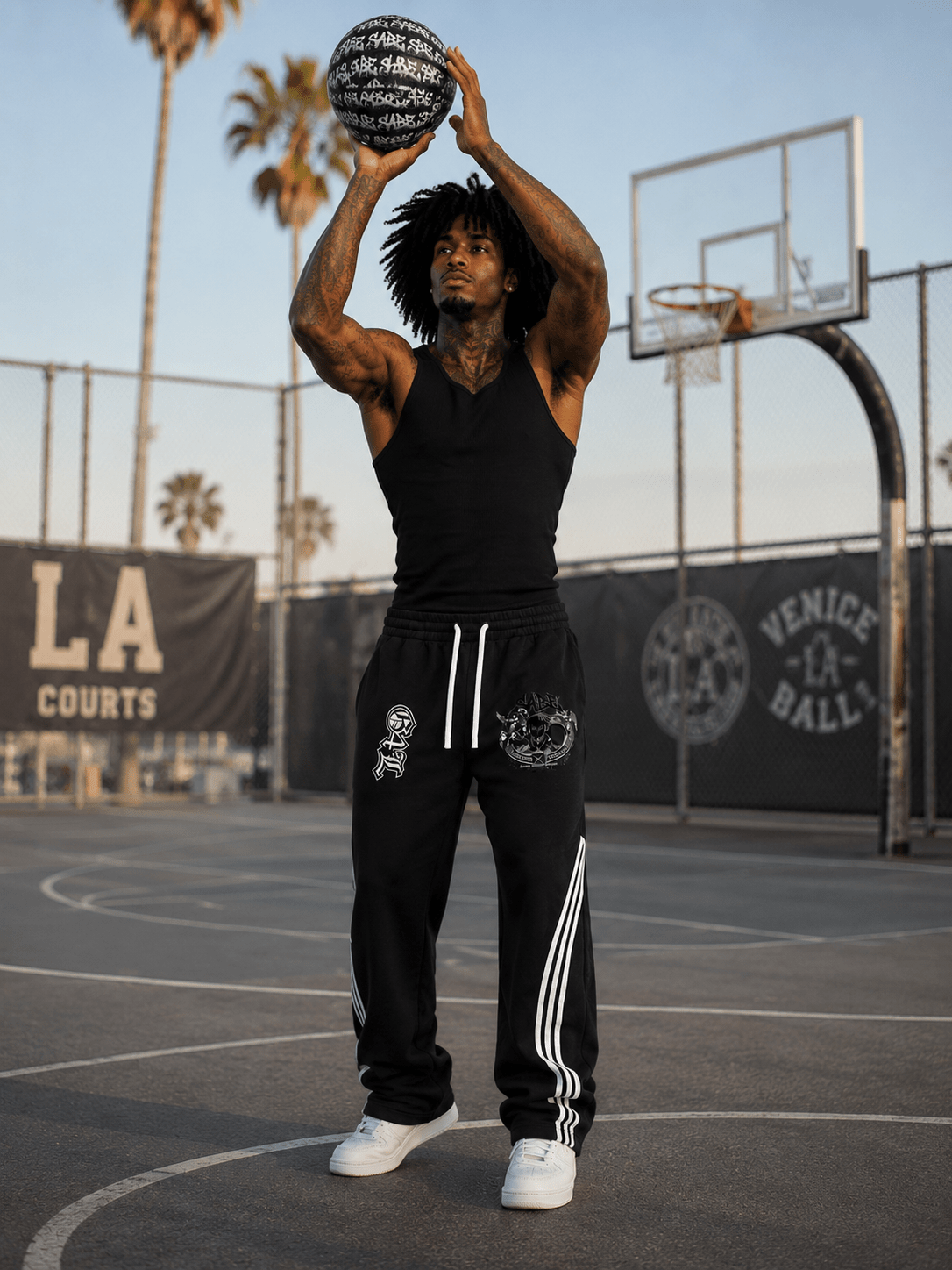 Person holding a basketball on a court with palm trees and 'LA Courts' in the background
