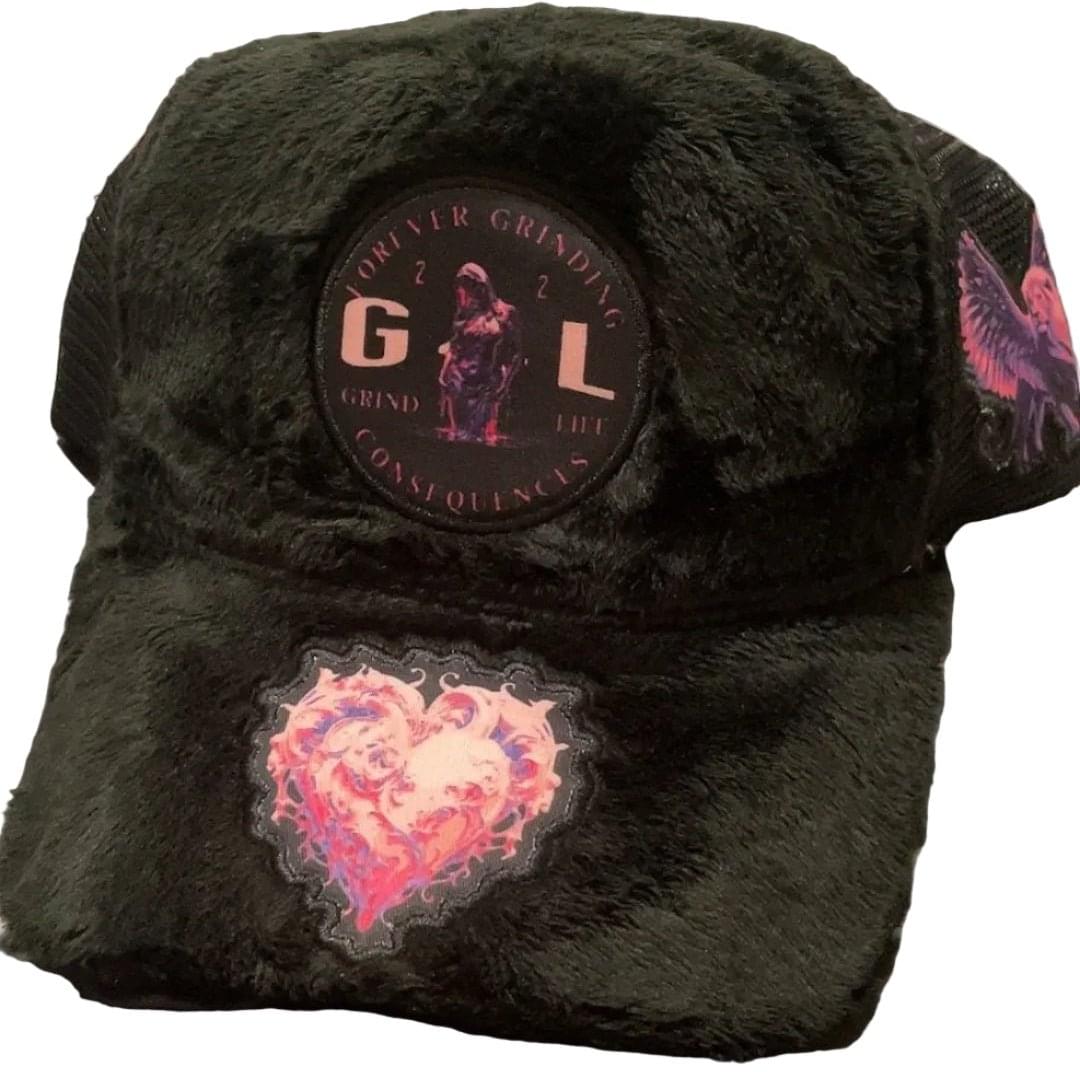 Black plush hat with decorative patches on a white background